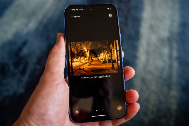 A hand holds a smartphone displaying a photo of a brightly lit street at night. The screen shows options for editing the photo. A message in the middle of the screen reads, "Something not right? Send feedback.